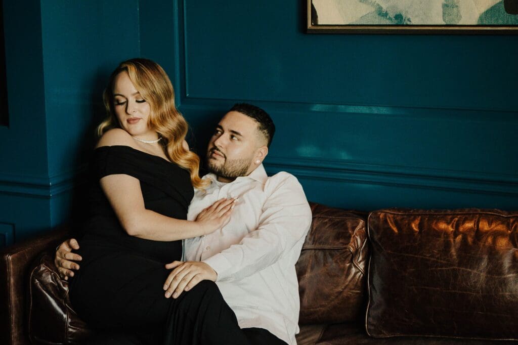 man and woman sitting on couch for glam photo session