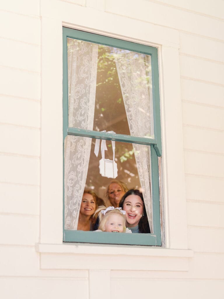 Wedding party looks on at the bride during wedding photos with professional glam.